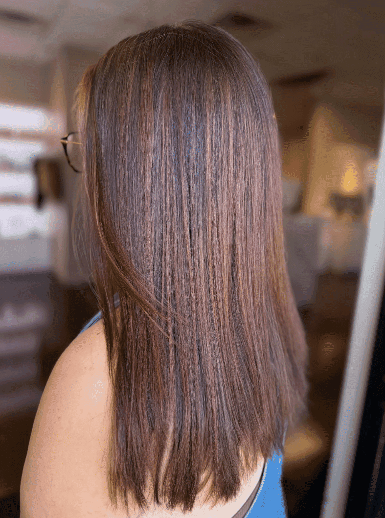Smooth, straight brown hair with subtle highlights, shown from the side in a salon setting.