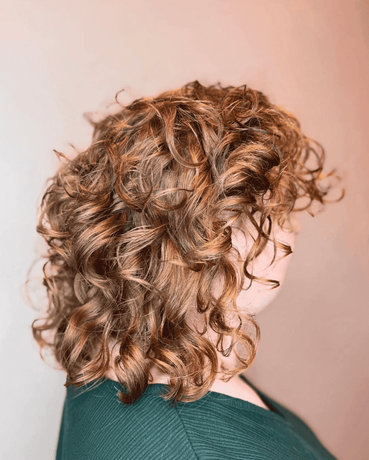 Curly red hair styled with layers, shown from the side against a neutral background.